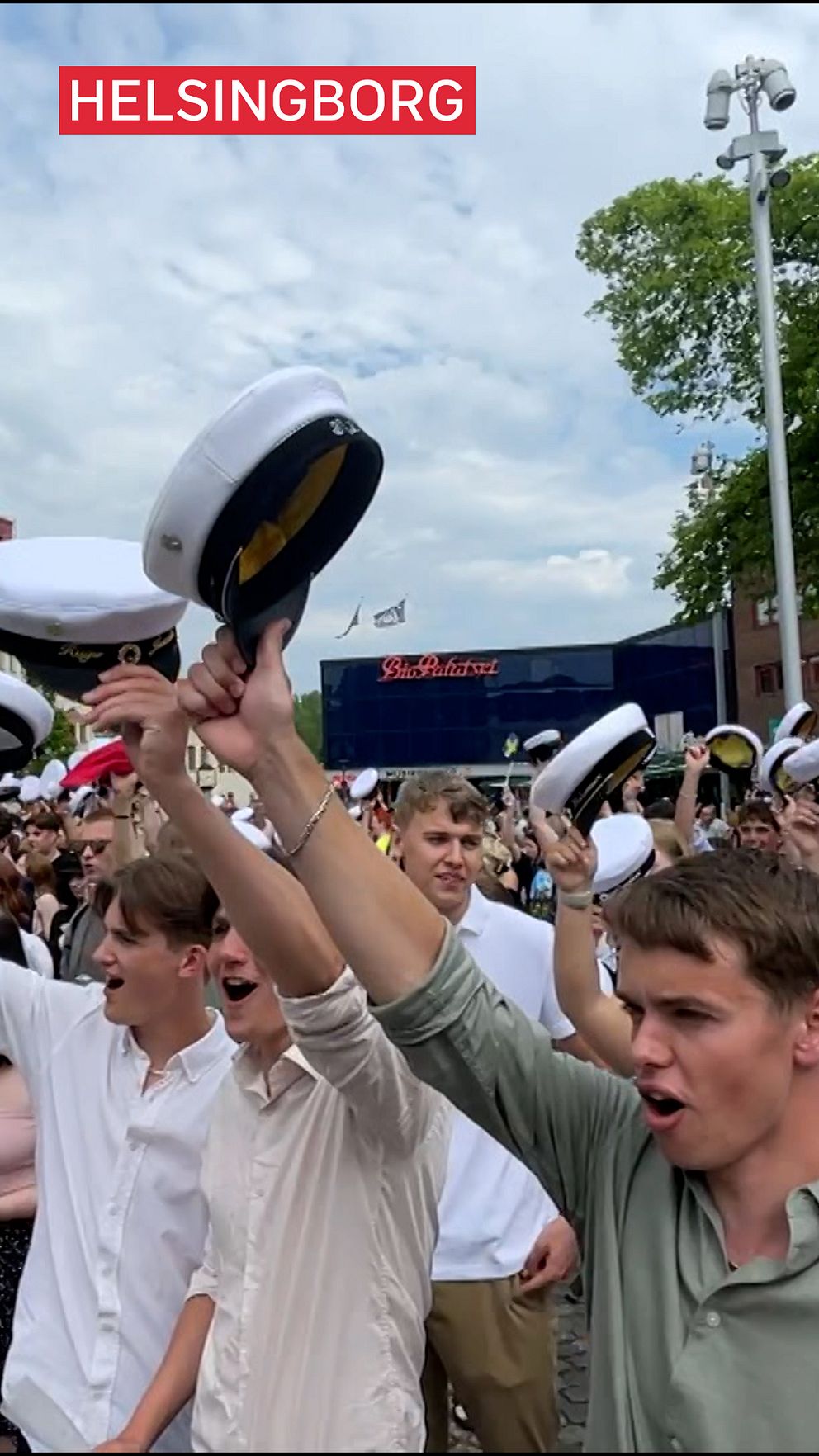 Folk i Helsingborg firar examen, lyfter studentmössor i luften.
