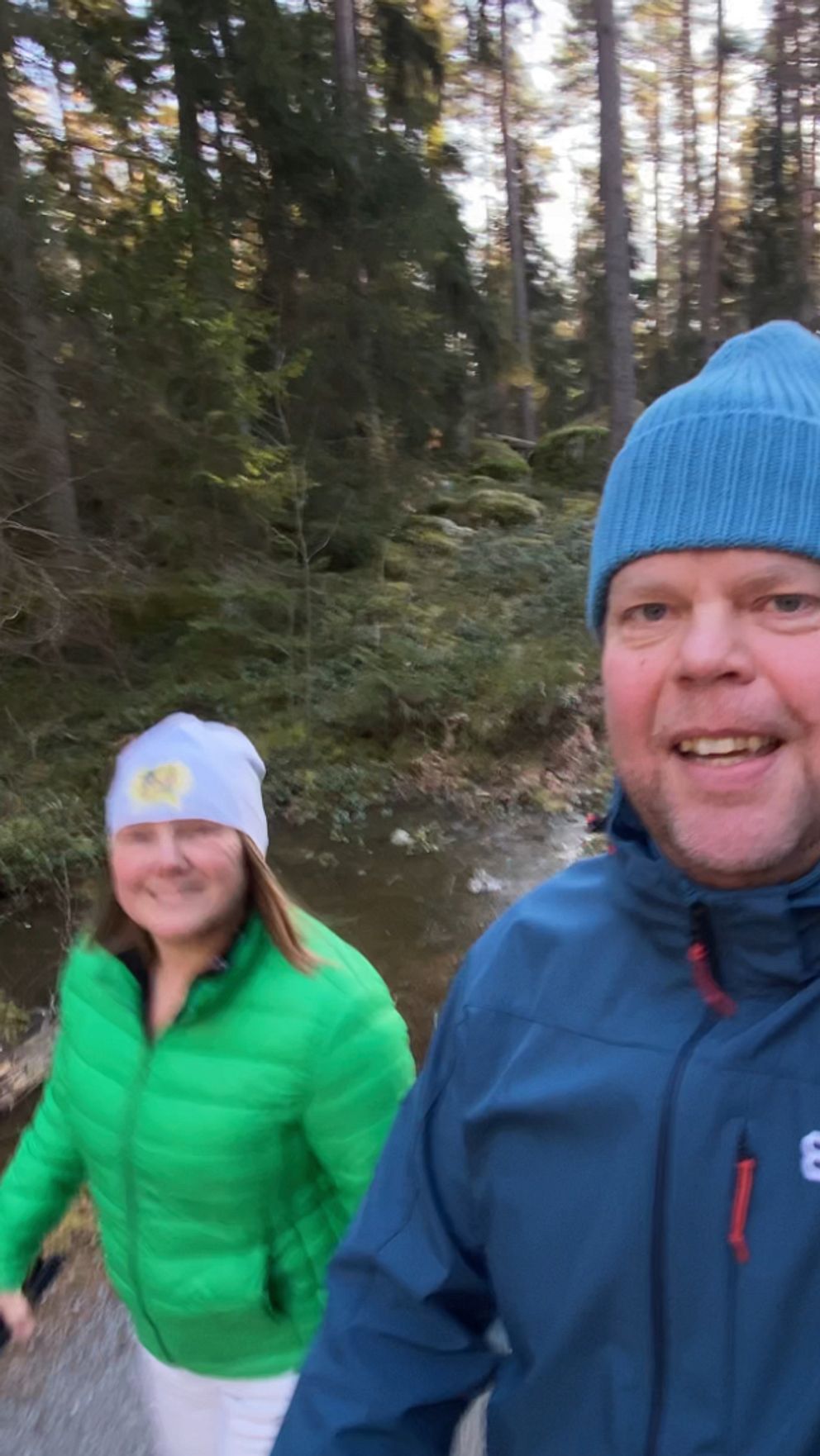 En delad bild: Till vänster syns två personer som promenerar i en skogsklädd miljö, iklädda vinterkläder. Till höger håller en person upp en smartphone som visar en tidmätning på 1659,94 sekunder.