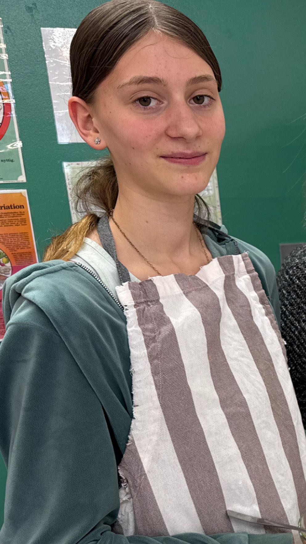 Två unga personer med randiga förkläden lagar mat tillsammans i ett kök.
