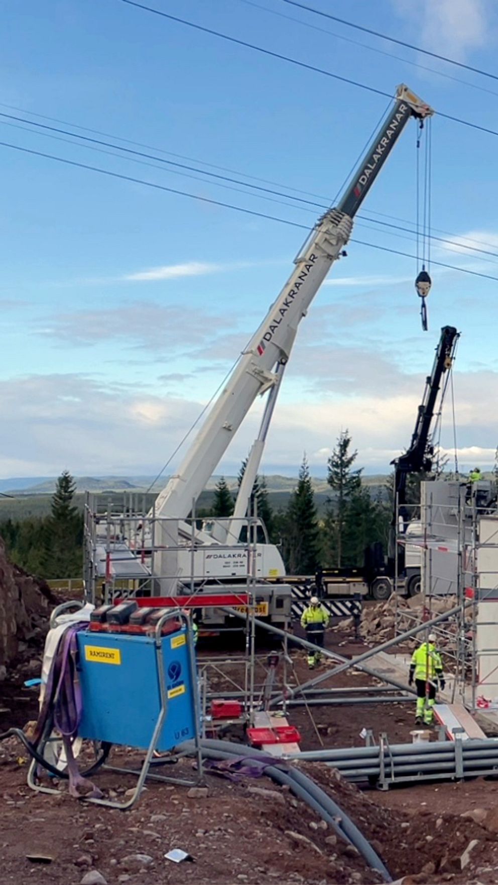 En delad bild med två sektioner. Den vänstra sektionen visar en byggarbetsplats med en stor kran som lyfter material, omgiven av arbetare i skyddskläder och byggutrustning.Den högra sektionen visar en man i grön jacka stående i en utomhusmiljö.