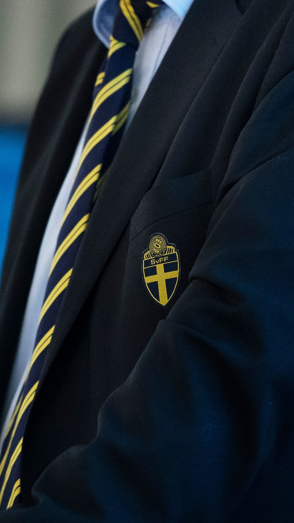 Två personer i kavaj med Svenska Fotbollförbundets emblem och gulrandiga slipsar.