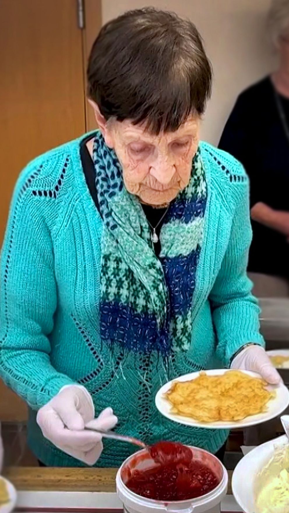 En delad bild med två sektioner: den vänstra visar en kvinna i blå tröja som serverar mat på en tallrik, med flera skålar med olika rätter i bakgrunden, medan den högra sektionen visar en kvinna klädd i röd tröja med glittrande detaljer som sitter i en stol, omgiven av festlig dekoration.