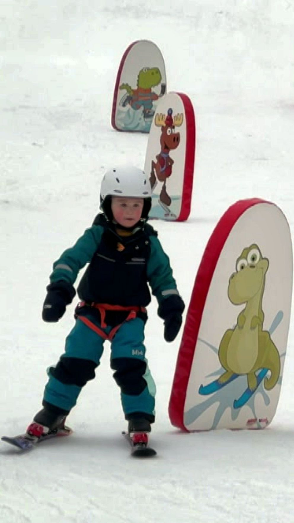 Två personer åker skidor genom en hinderbana på en snötäckt backe.