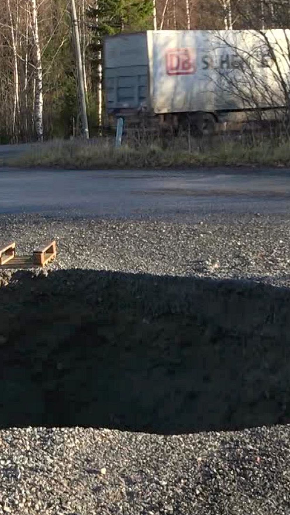 En delad bild som visar två scener. Till vänster syns en stor hålighet i vägbanan vid en väg med en lastbil i bakgrunden. Tre fåglar står på vägen i närheten av hålet. Till höger sitter en person i en lastbil med en orange väst på.