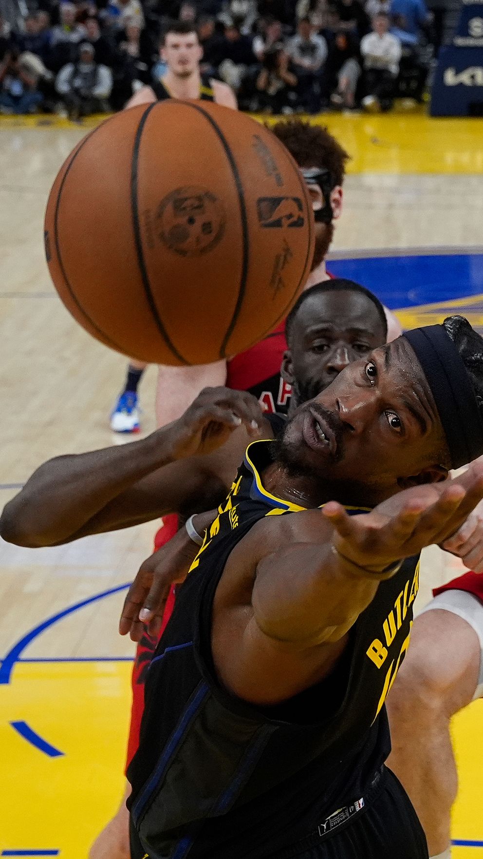 Basketspelare kämpar om bollen under intensiv match.