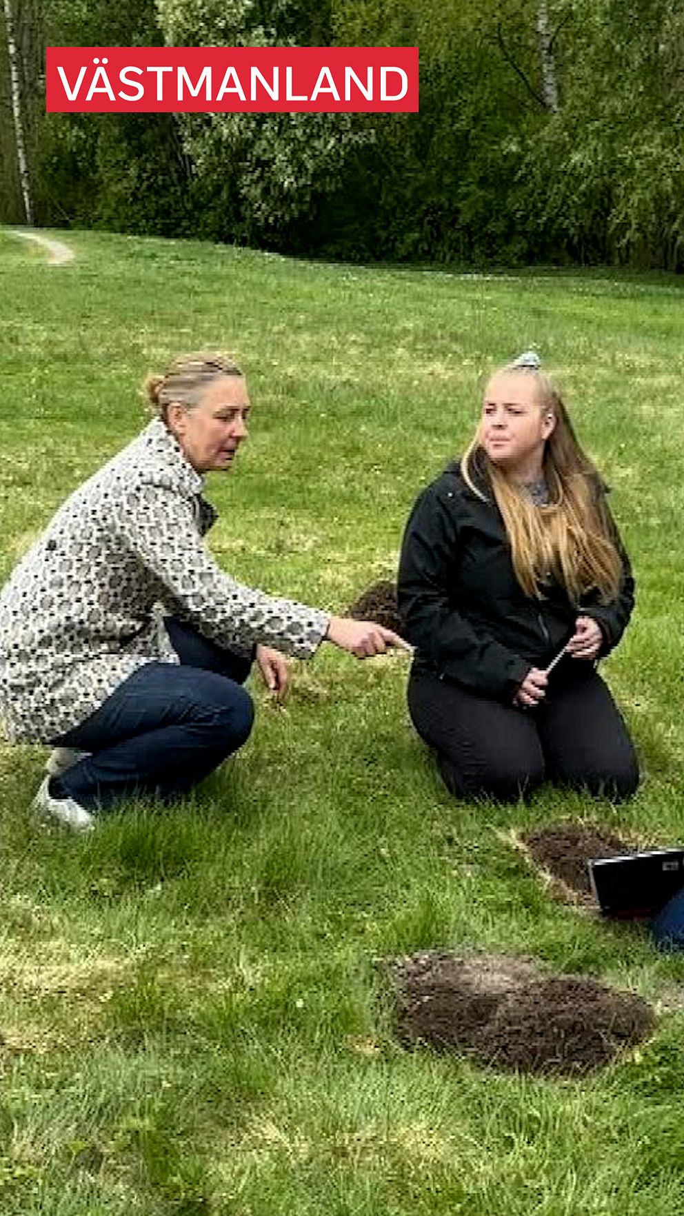 En person pratar med en annan utomhus på en gräsmatta med gropar i, i Västmanland.