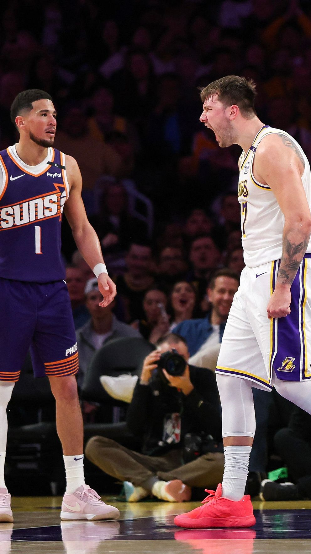 Basketspelare från Lakers och Suns diskuterar under en match på spelplanen.