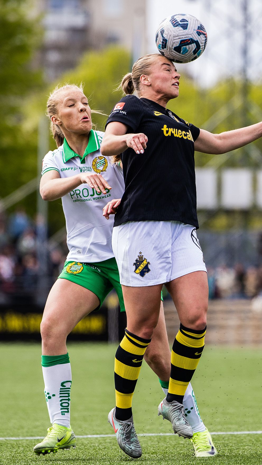 Två fotbollsspelare tävlar om bollen under en match på en utomhusplan.