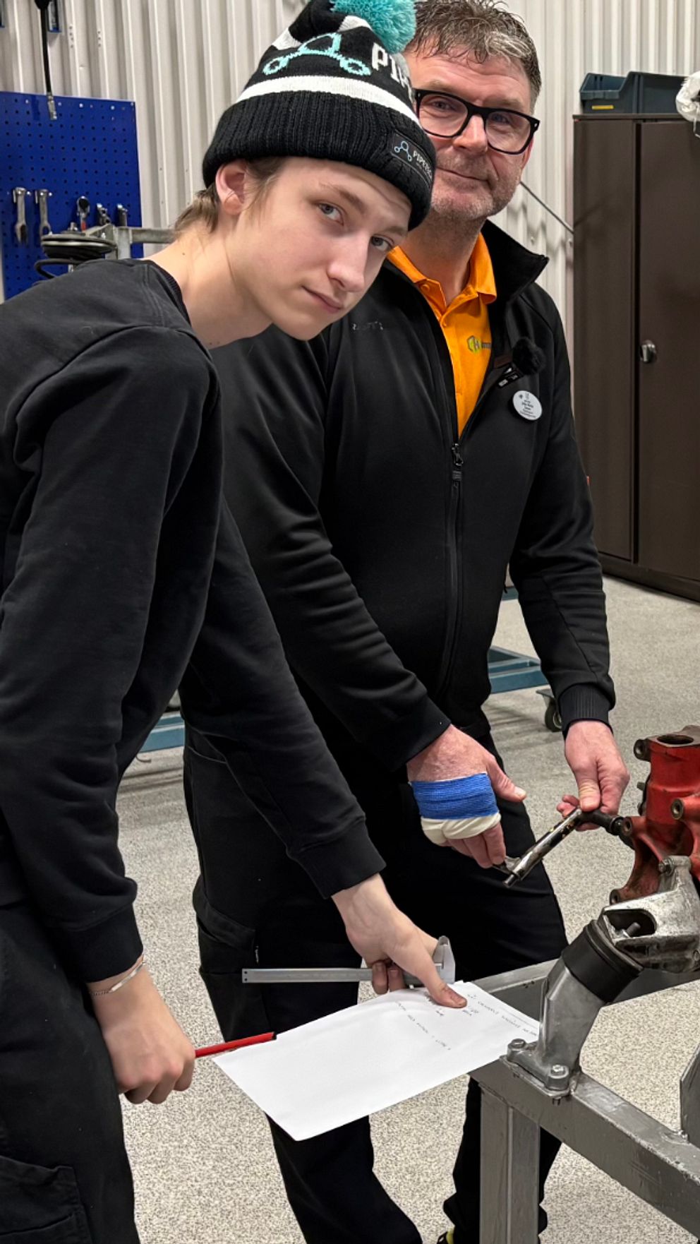 två yngre och två äldre personer som står runt ett motorblock