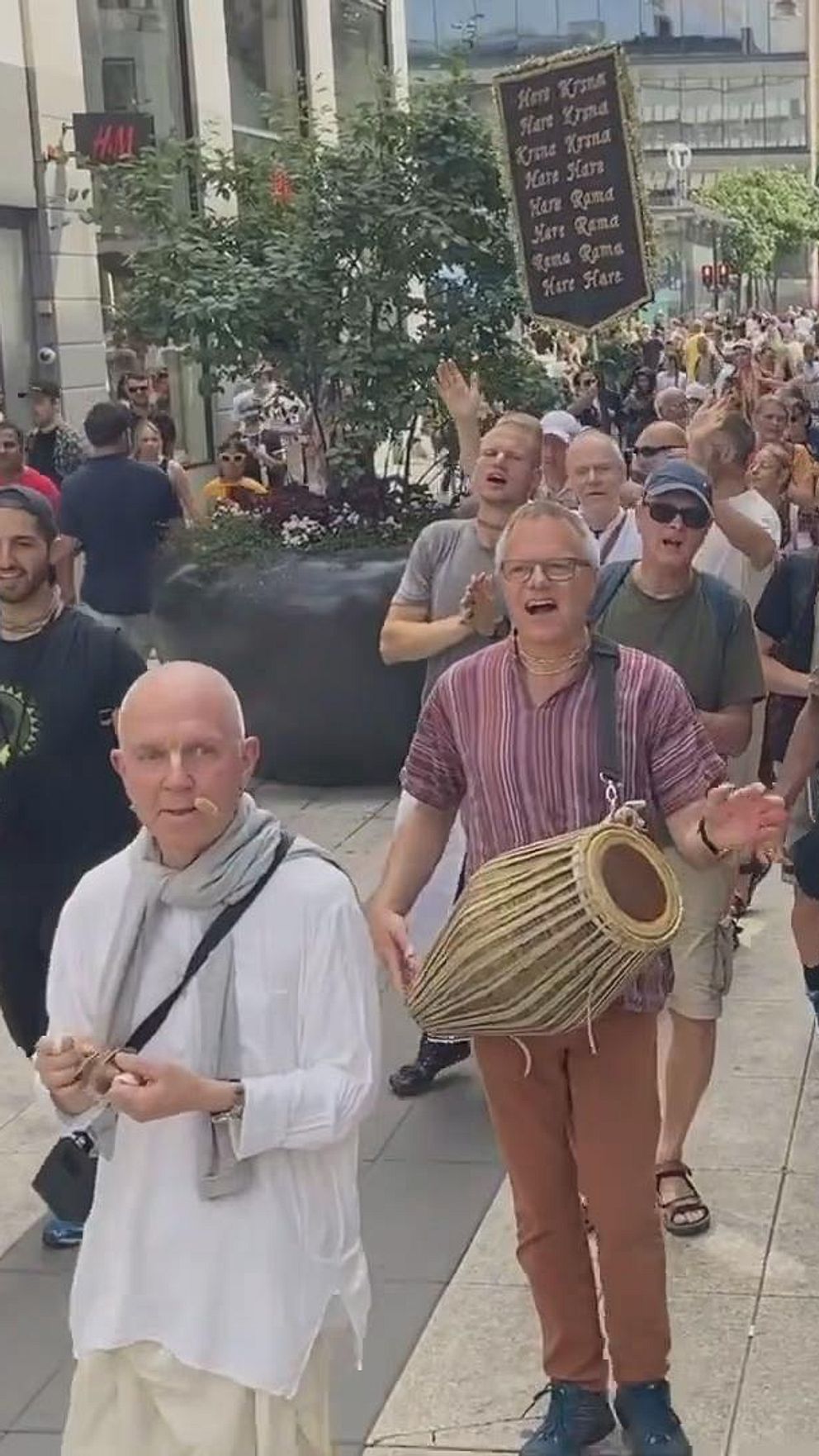 Folkmassa marscherar på en stadsgata, flera personer spelar trummor.