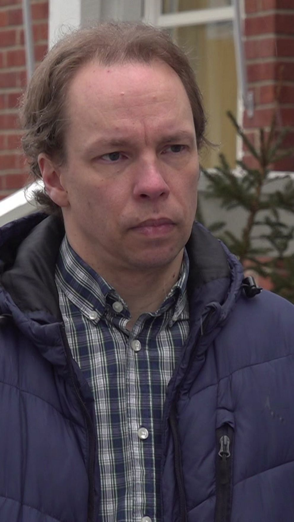 Reporter från SVT intervjuar person utanför tegelbyggnad.