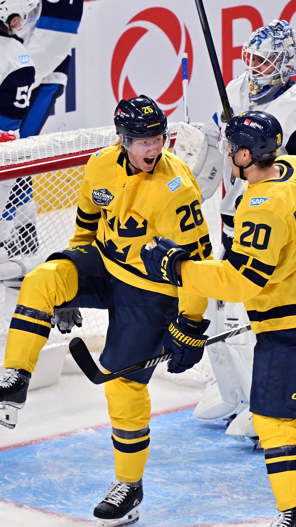 Tre svenska ishockeyspelare i gula tröjor firar ett mål framför motståndarlagets målvakt och en försvarare.