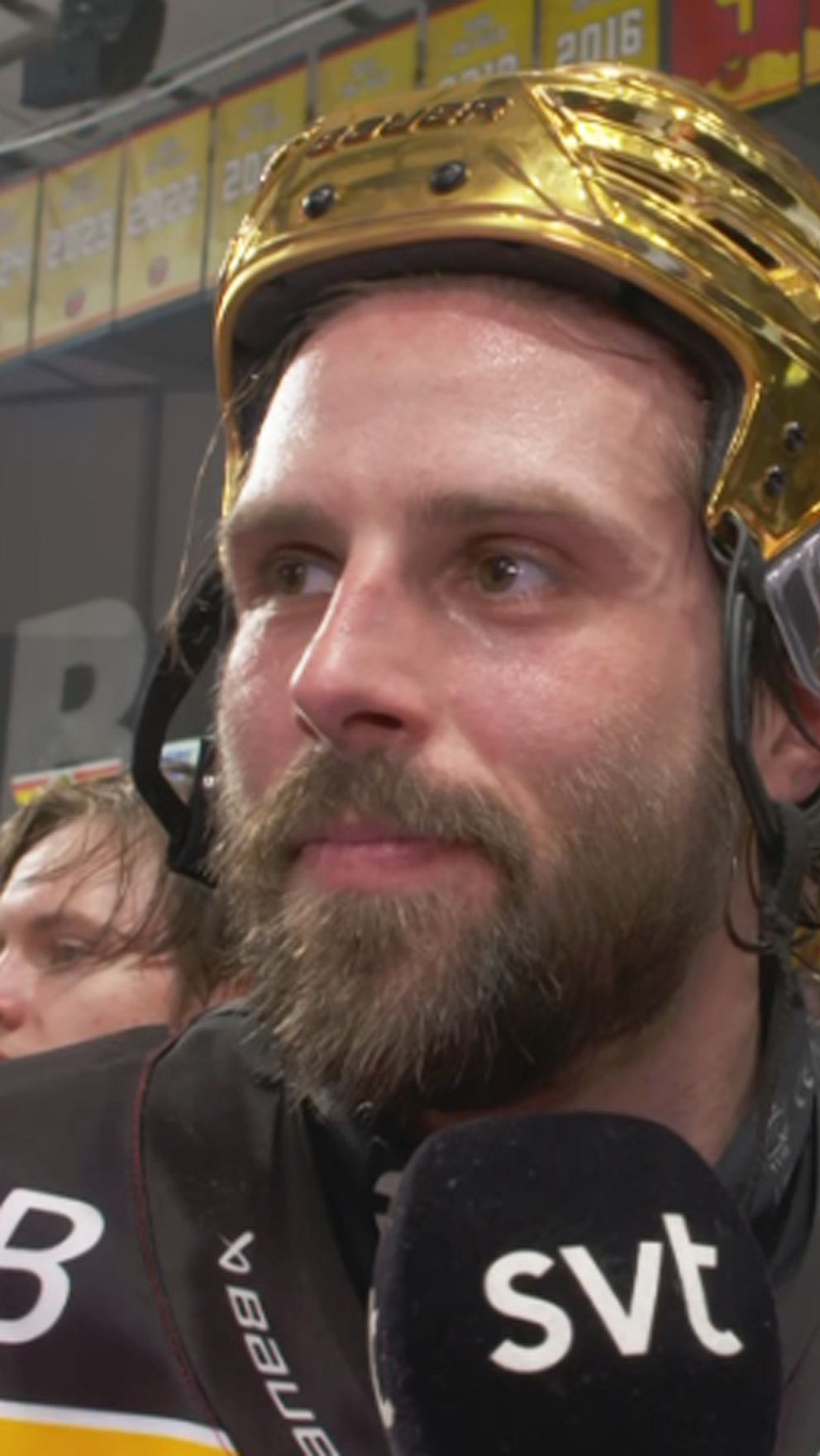 Ishockeyspelare med guldhjälm intervjuas av SVT efter match i fullsatt arena.