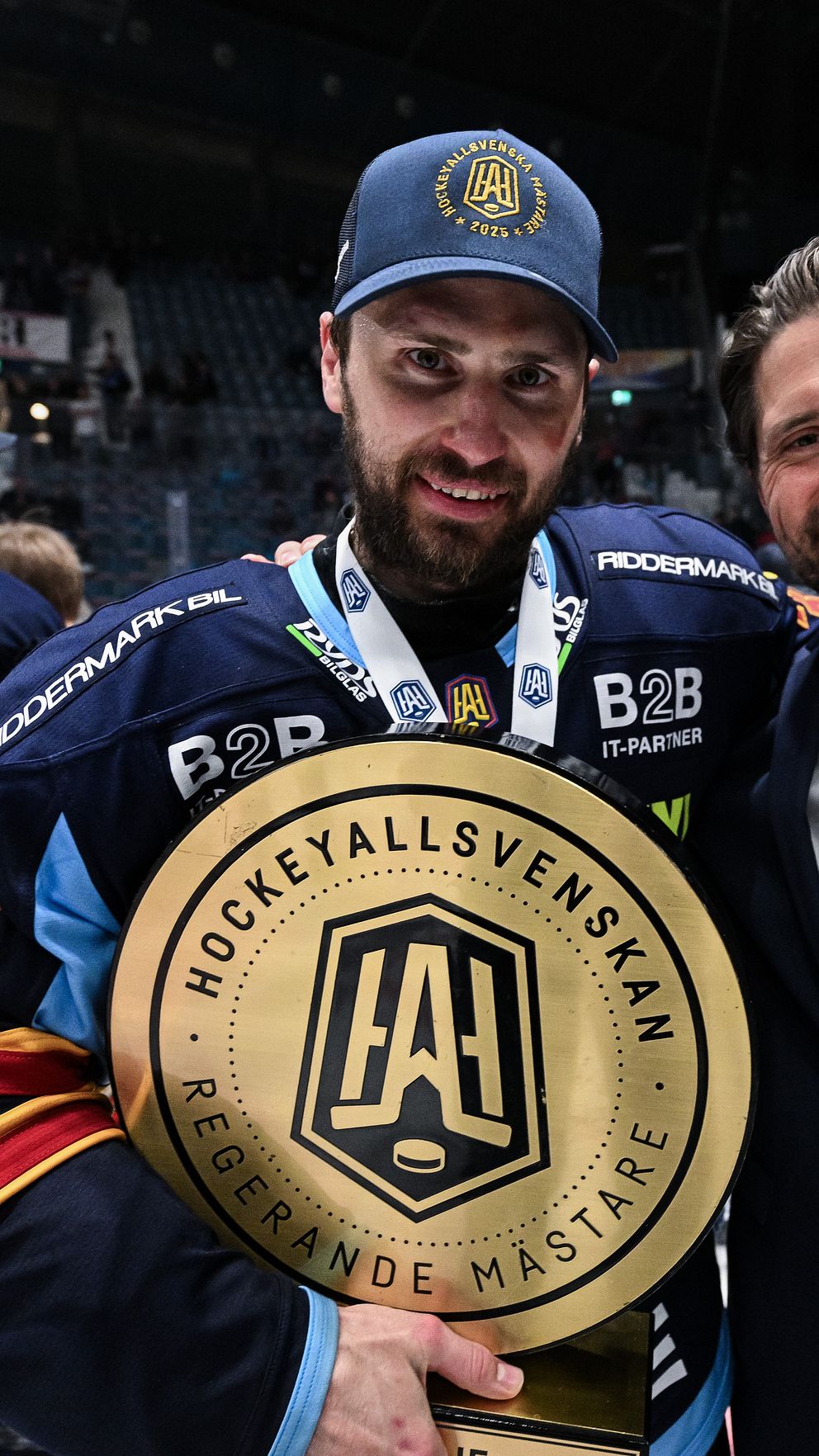 Två personer firar med Hockeyallsvenskans vinnarplakett på isen efter finalen.