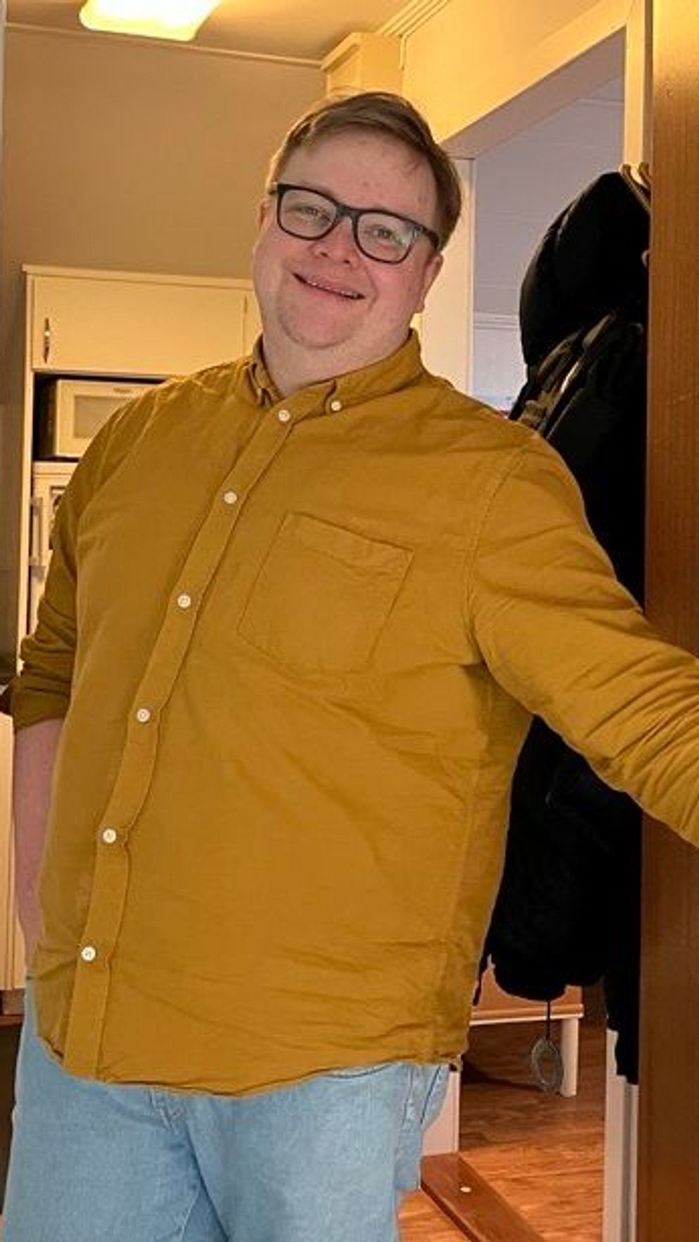 Man i gul skjorta öppnar dörren i ett trapphus.