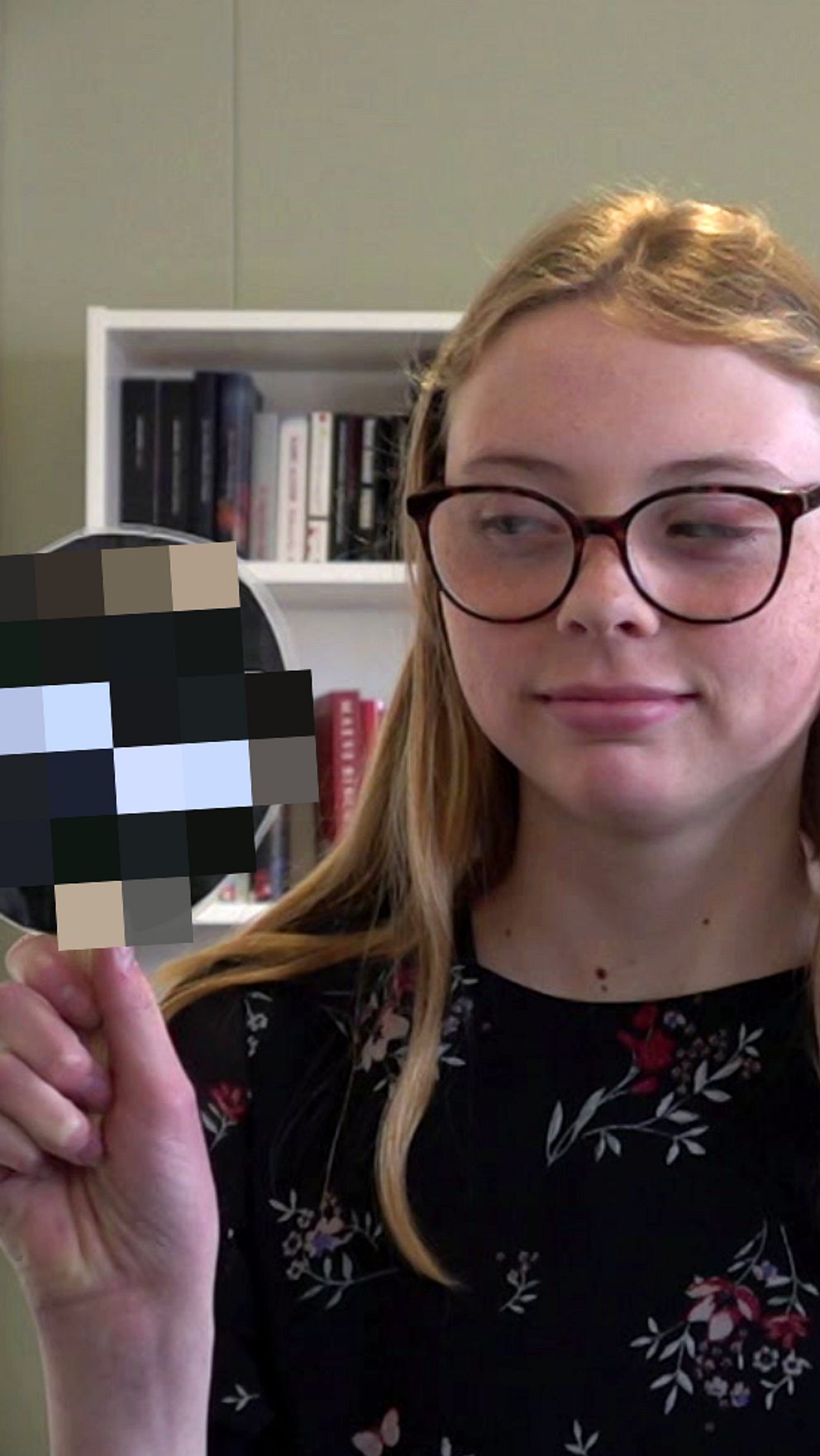 Tjej håller upp skylt som hon tittar på.