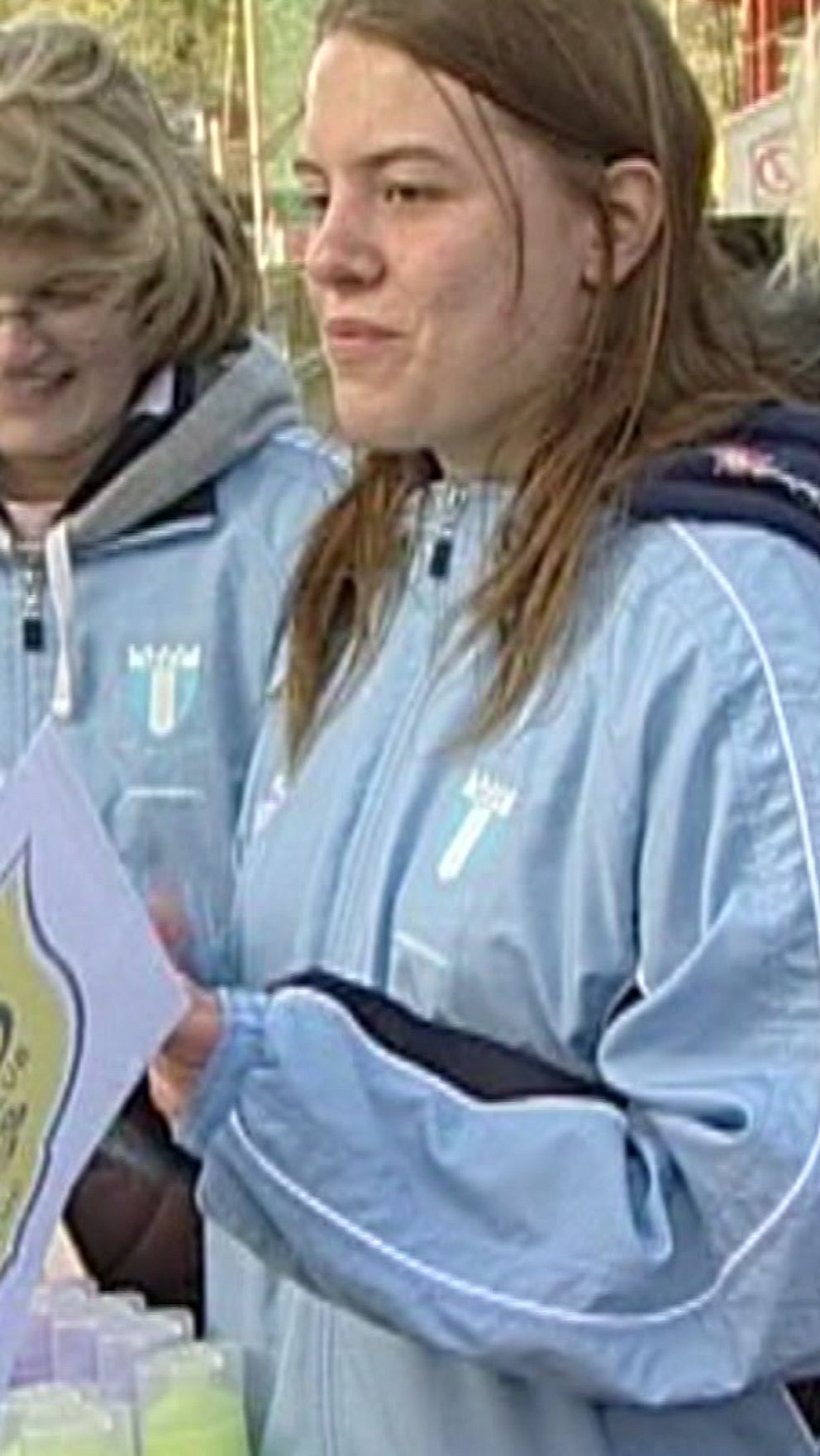 Unga kvinnor med MFF-tröjor håller i gula flaggor med LdB-loggan på.