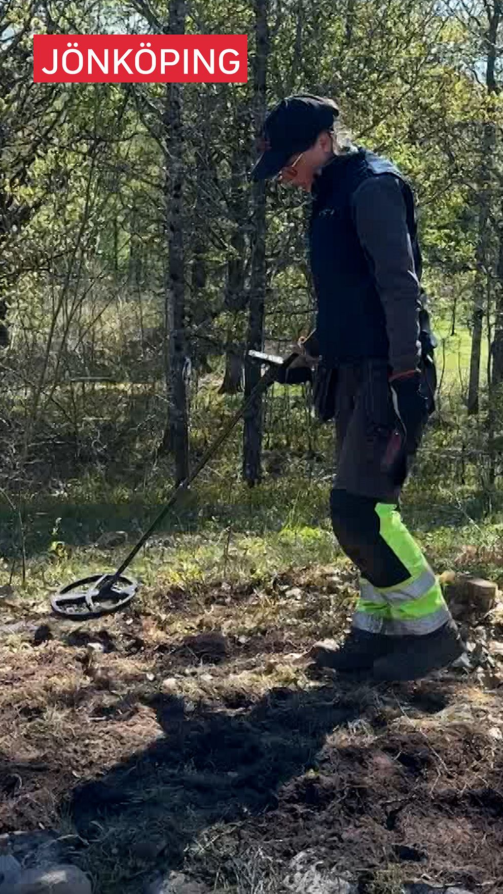 Person söker med metalldetektor på mark i skogsområde i Jönköping.