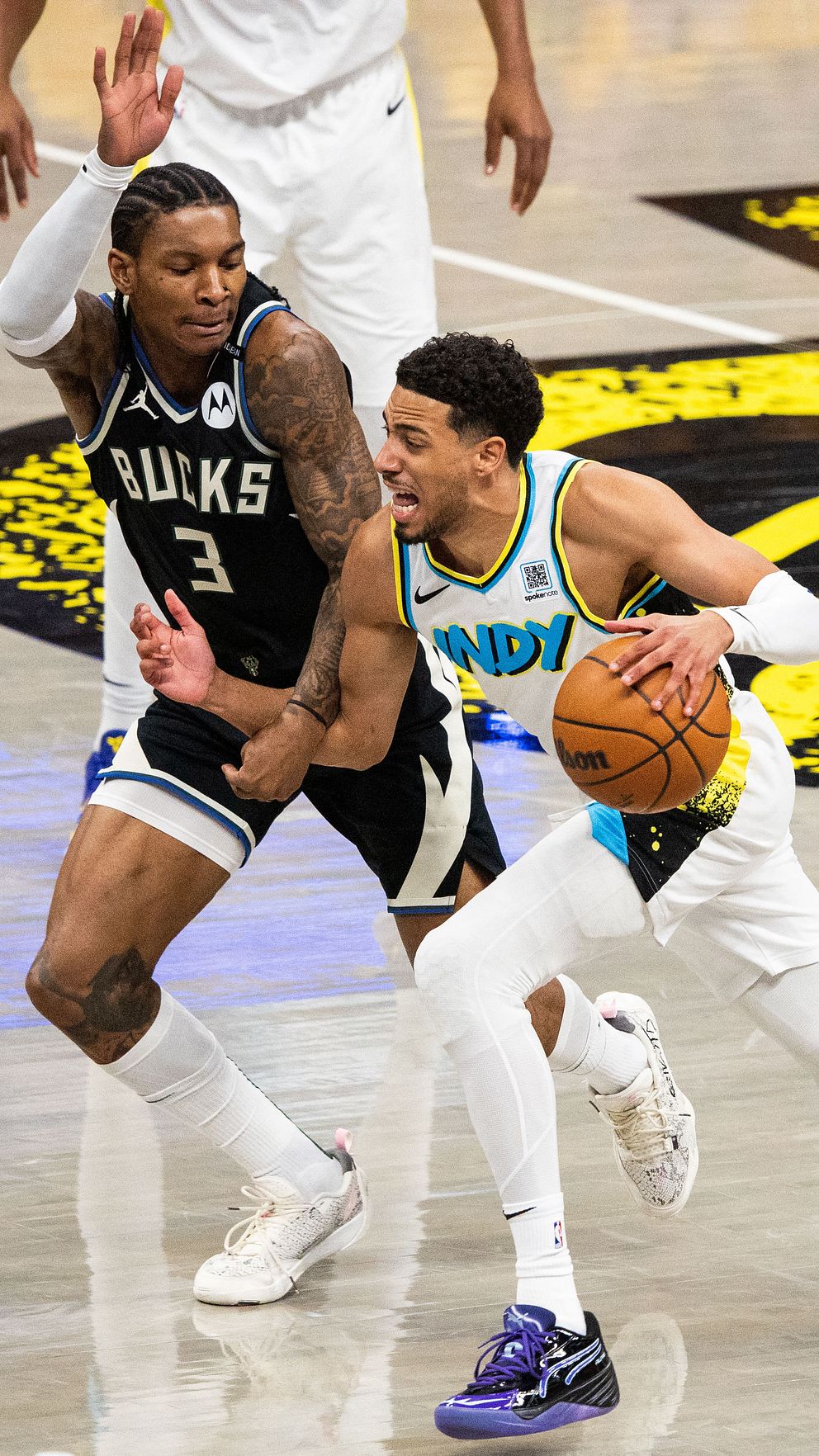 Två basketspelare i närkamp under en match, en försöker dribbla förbi sin motståndare.
