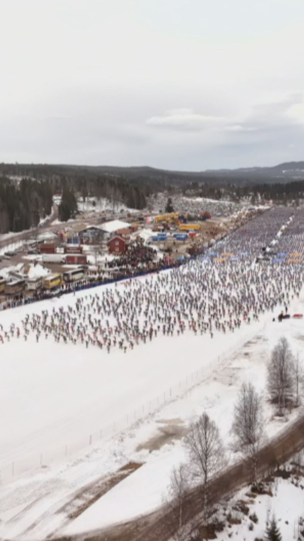 Luftfoto av Vasaloppet med tusentals skidåkare på vita snötäckta spår genom vintrigt landskap.