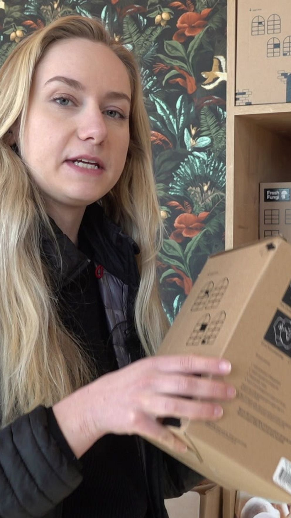 Person granskar förpackning i butik framför hylla med flera olika varor.
