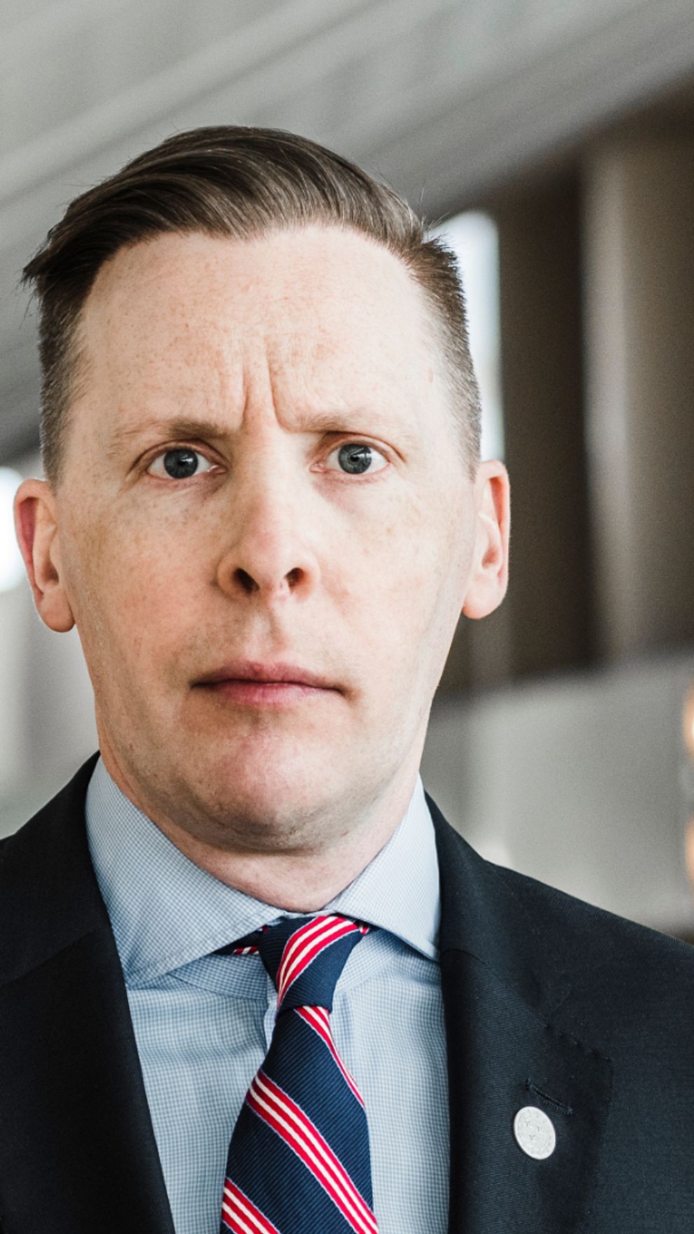 Mats Green ser allvarlig ut och tittar in i kameran. Kort brunt hår, slätrakad klädd i kostym.