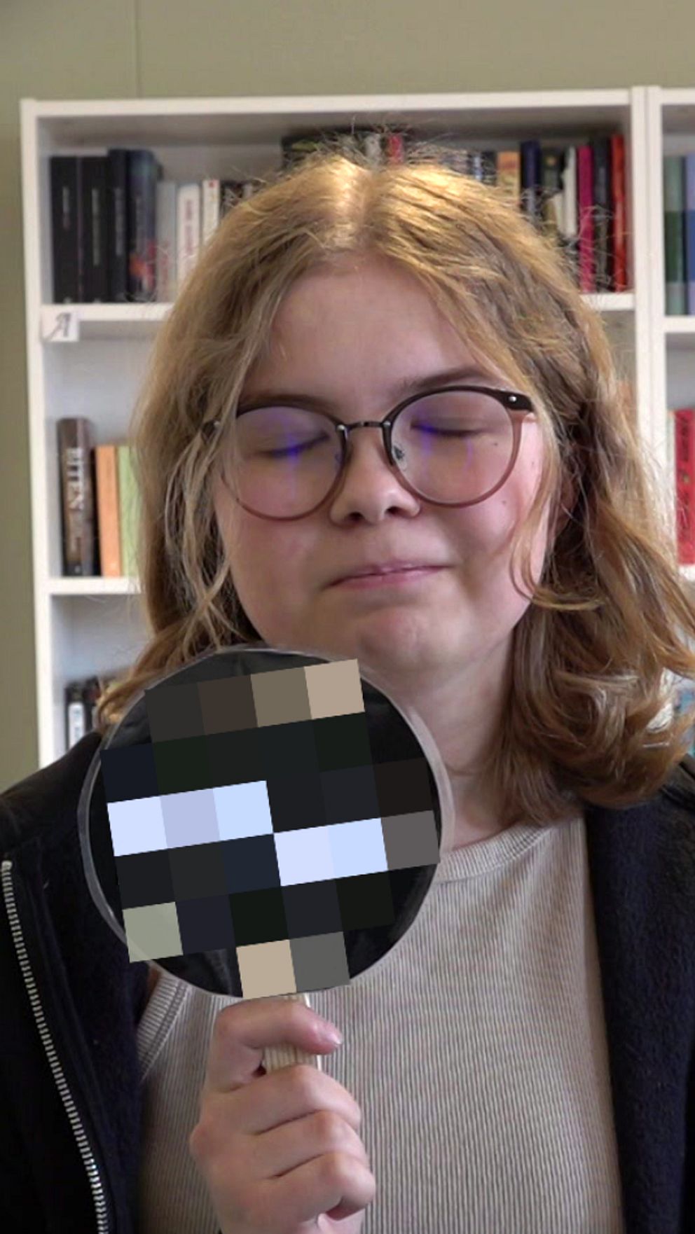 Tjej som blundar och håller upp en skylt.