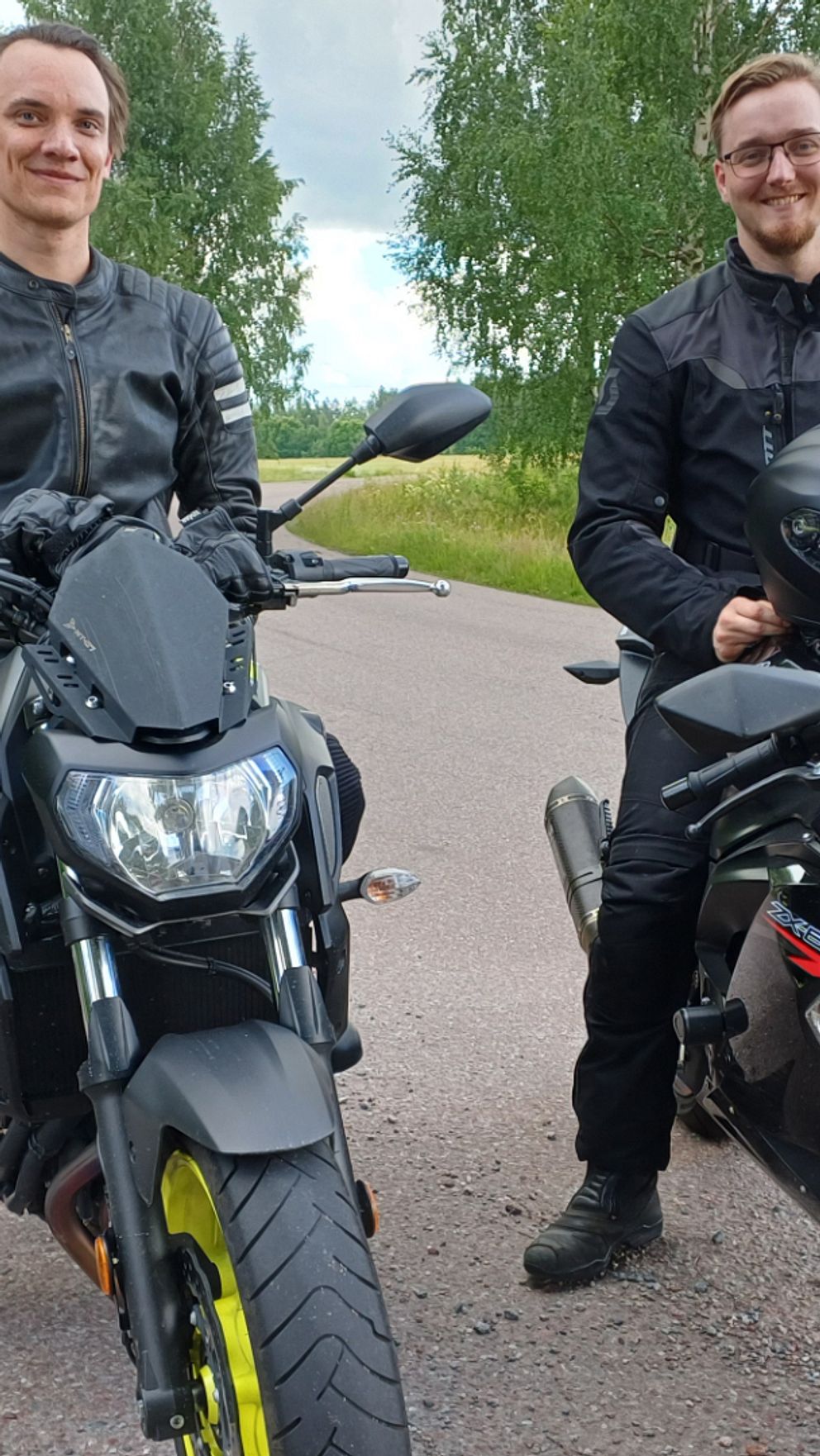 Två män sitter på sina motorcyklar bredvid en väg