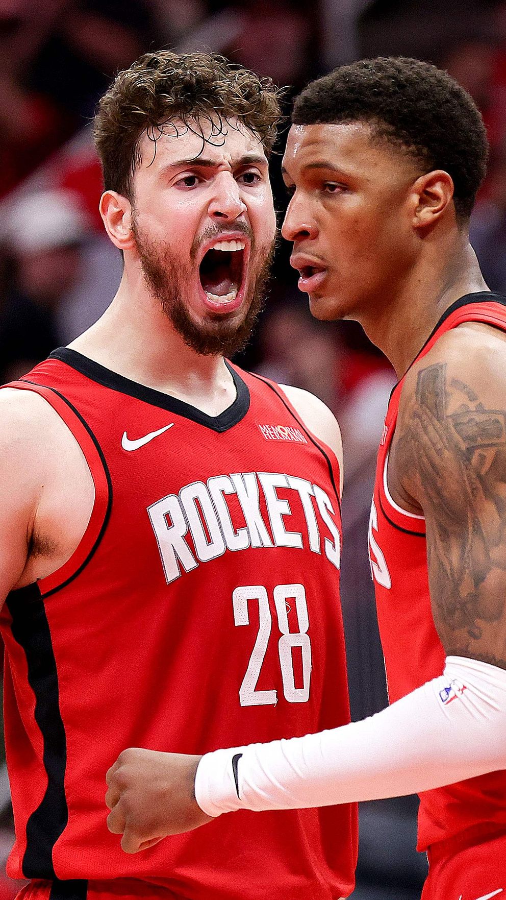 Två Houston Rockets-spelare i röd matchdräkt diskuterar på basketplanen.
