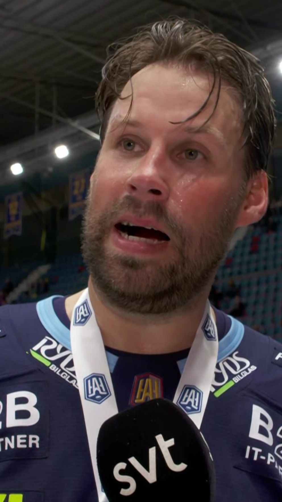 Ishockeyspelare intervjuas av SVT efter match, med medalj runt halsen i fullsatt arena.