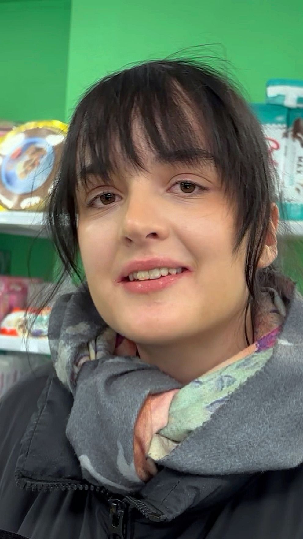 Person i en butik, omgiven av diverse matvaror på hyllor.