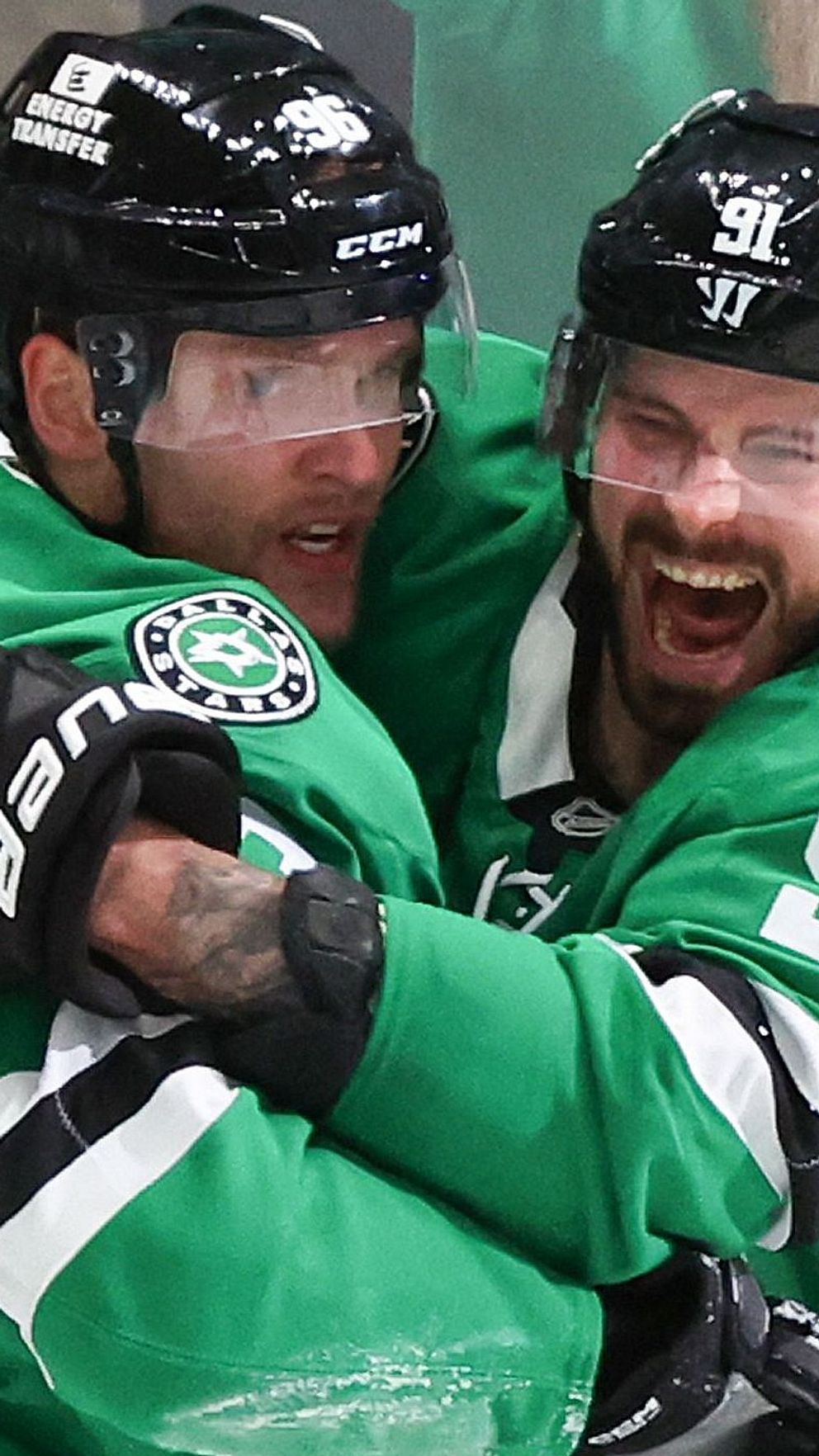 Två ishockeyspelare i gröna Dallas Stars-tröjor firar med en kram på isen.