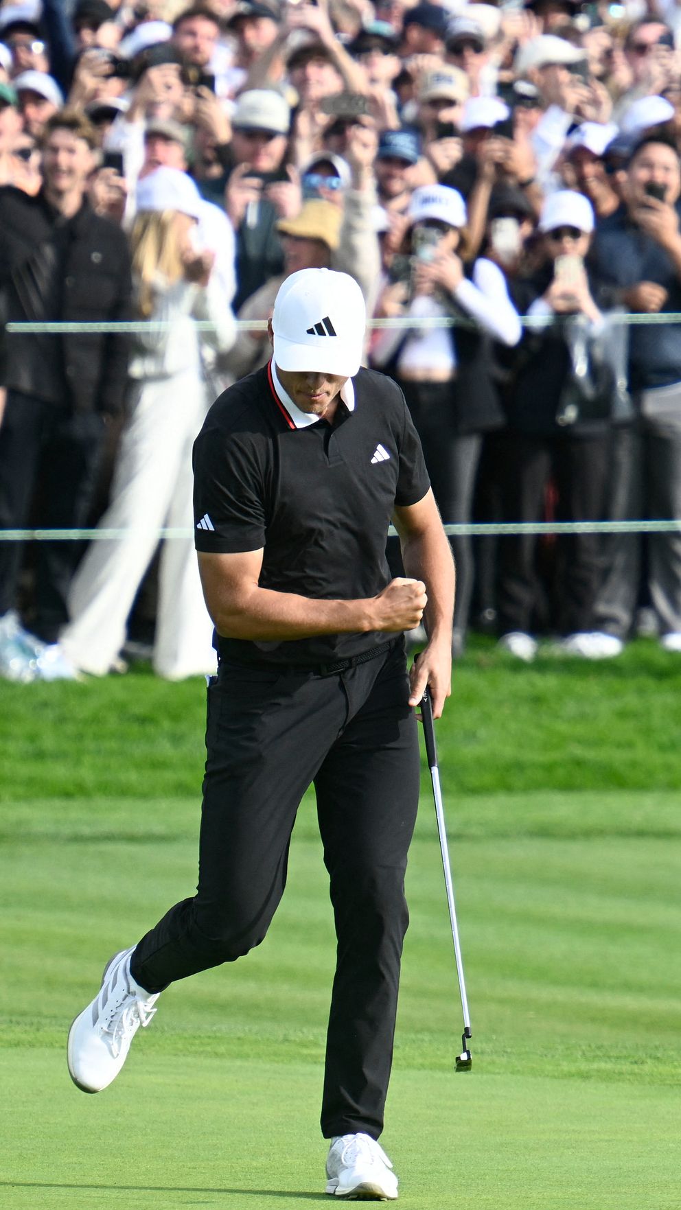 En golfspelare firar på greenen framför en stor publik.