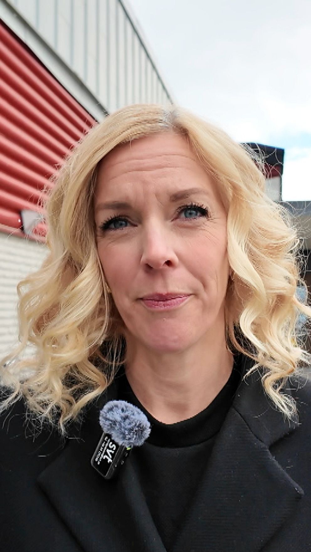 Person står utanför SVT:s byggnad, mikrofon synlig på rockslaget.