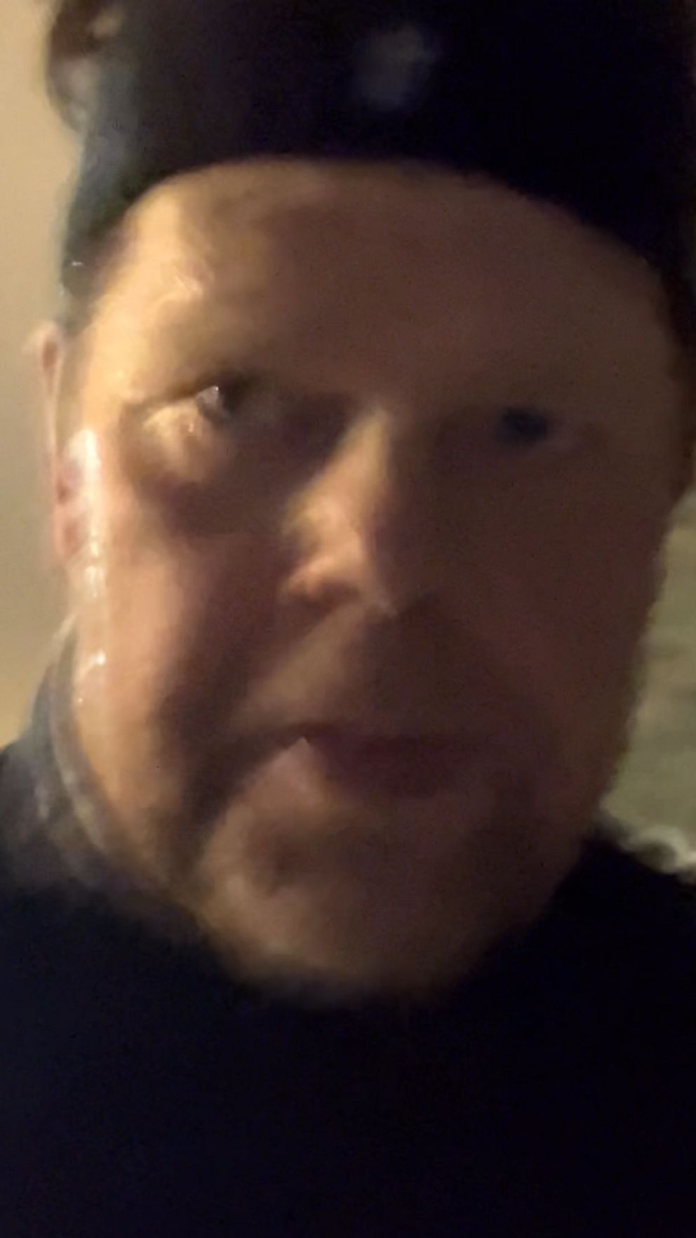 En nattscen med svagt upplysta träd i bakgrunden och ett suddigt, dunkel belysningselement till vänster.