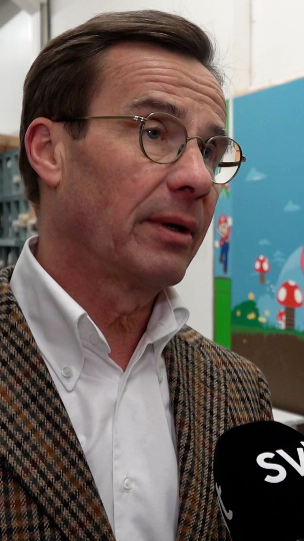En person intervjuas av SVT i färgrikt kontorsmiljö med hyllor och väggmålningar.