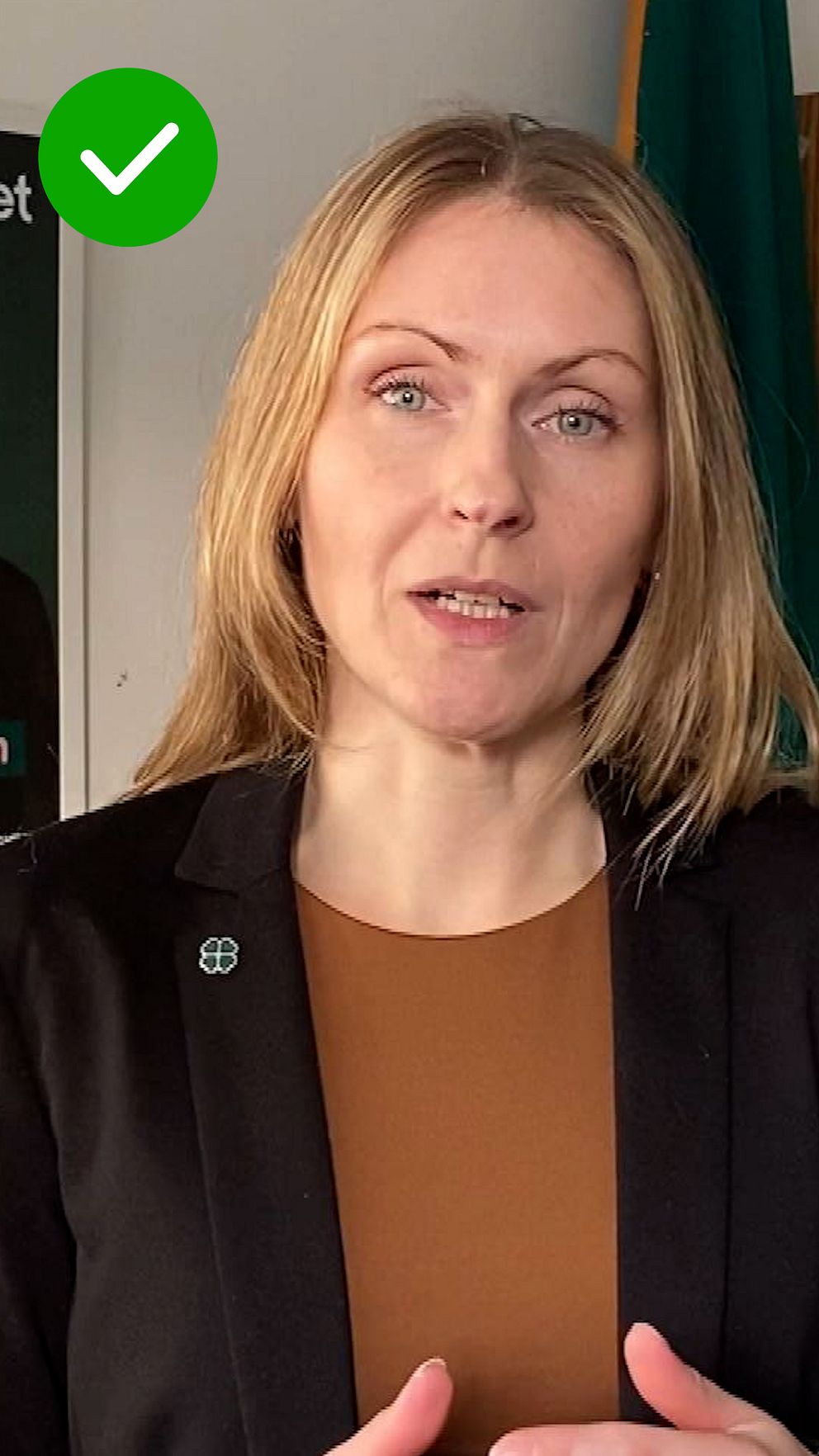 Person med blont hår i kavaj. I hörnet är en grön checkmark.