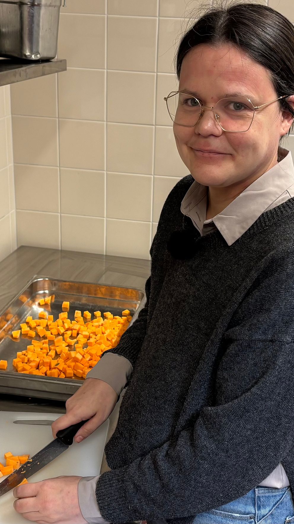 Maria Thulemark står vid en arbetsbänk i ett kök och skär upp grönsaker.