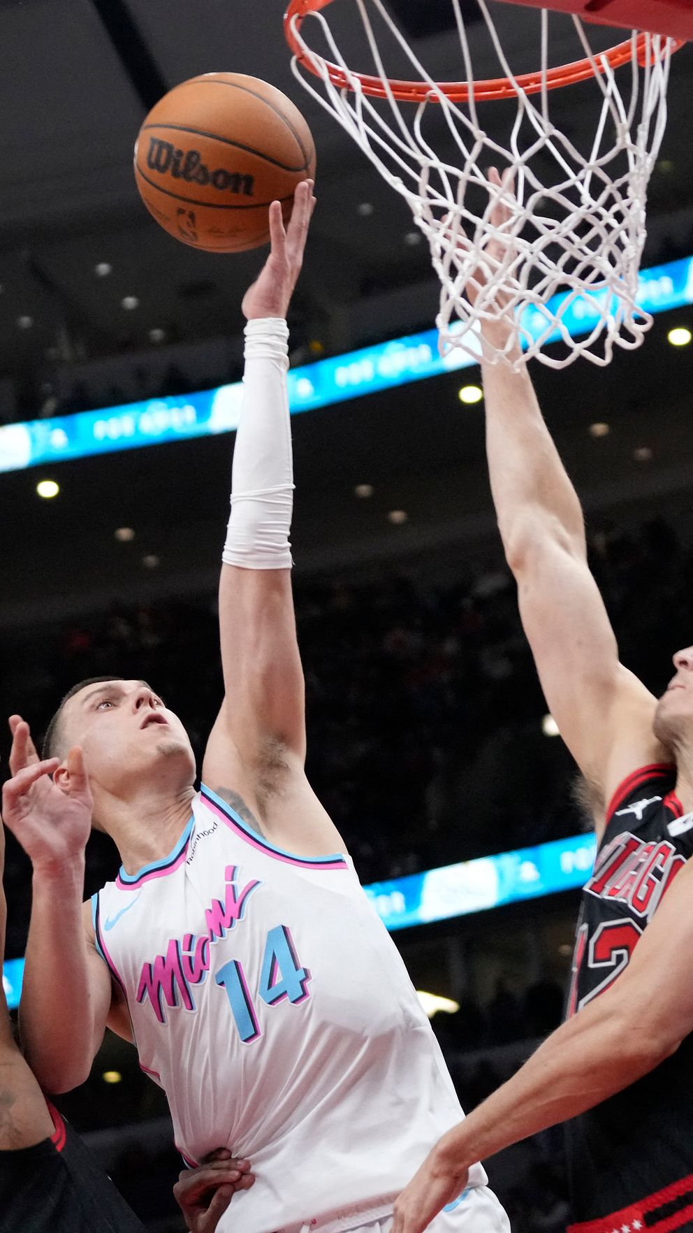 Basketspelare försöker göra mål medan två försvarare blockerar vid korgen.