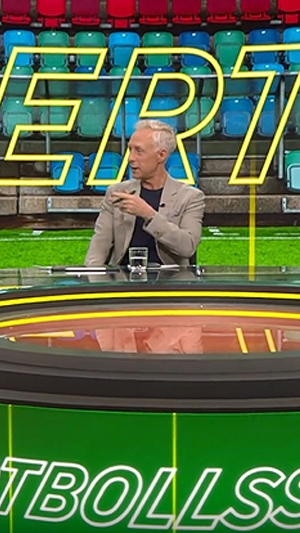 Tre personer diskuterar fotboll i en tv-studio med texten ”OVERTID” i bakgrunden.