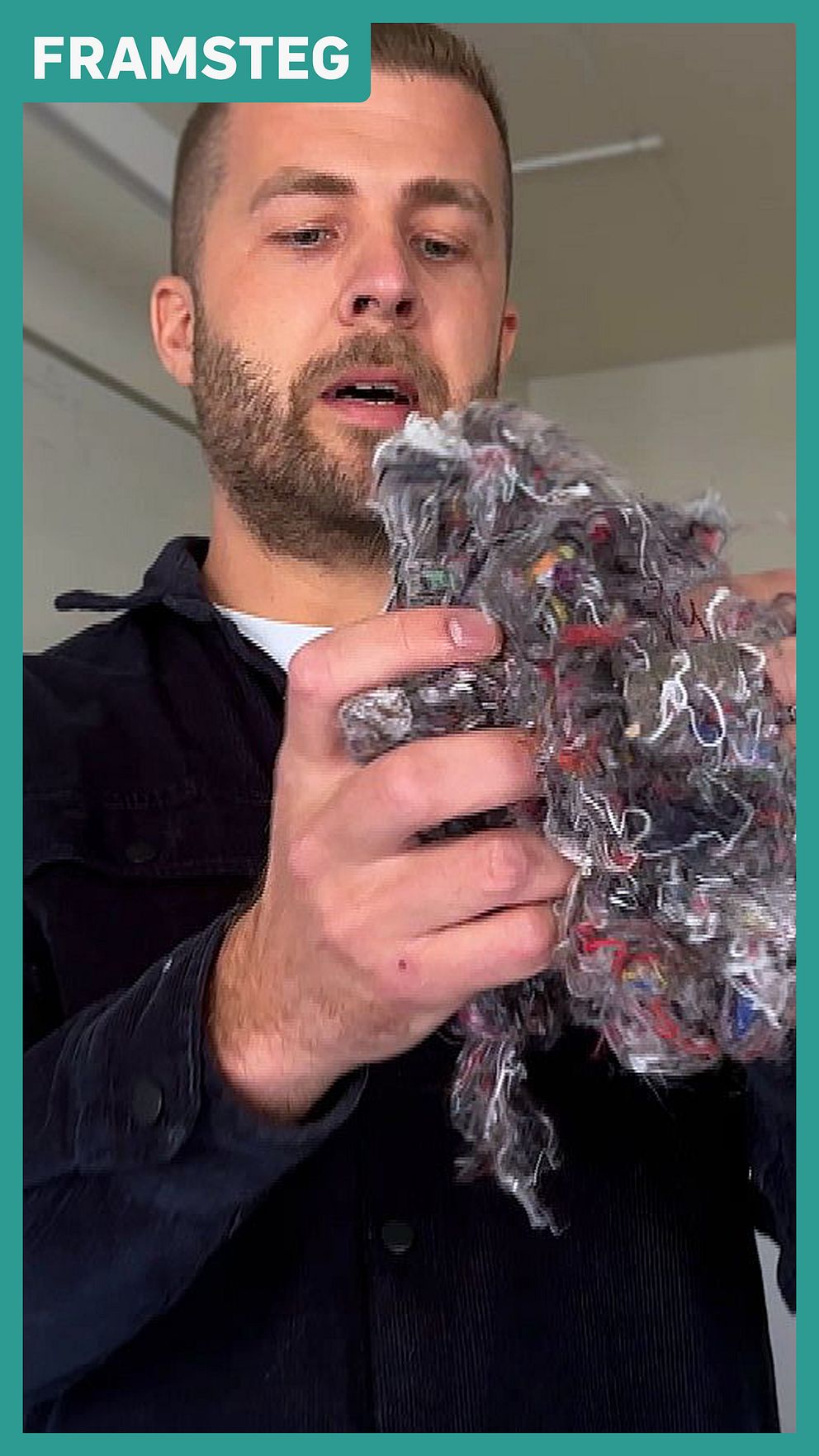 Person håller upp en bunt återvunnet textilmaterial i en inomhusmiljö.