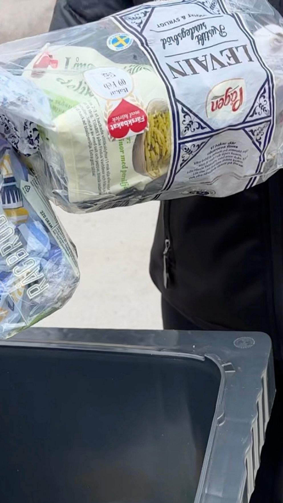Person återvinner plastförpackningar i återvinningsbehållare.