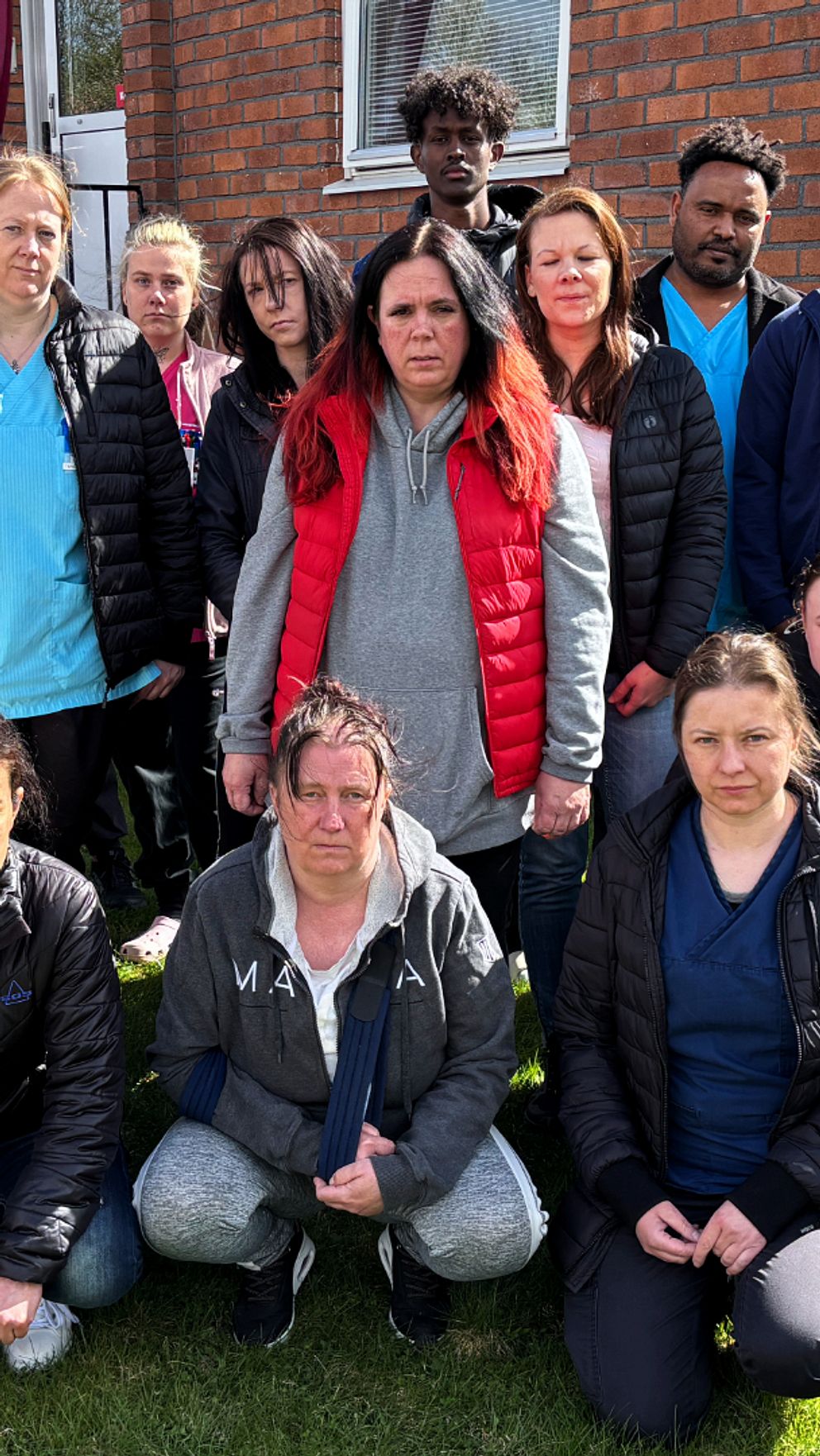Gruppbild utomhus med vårdpersonal framför en tegelbyggnad.