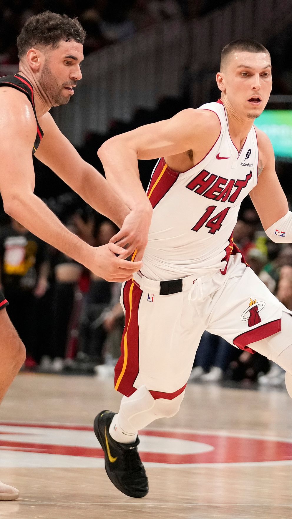 Två basketspelare tävlar om bollen under en match på basketplanen.