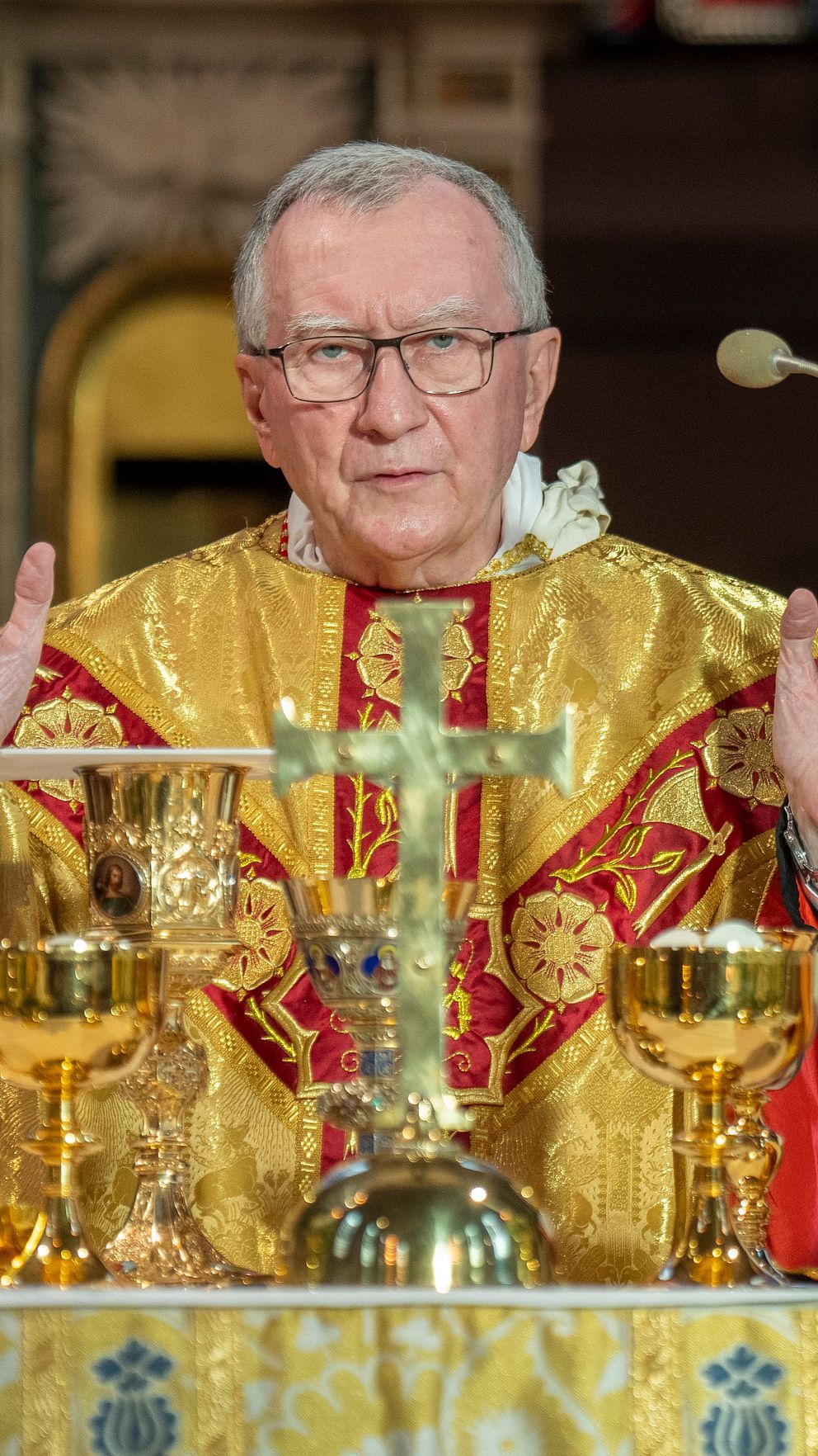 Präster leder gudstjänst bakom altare dekorerat med ljus och blommor i kyrkan.