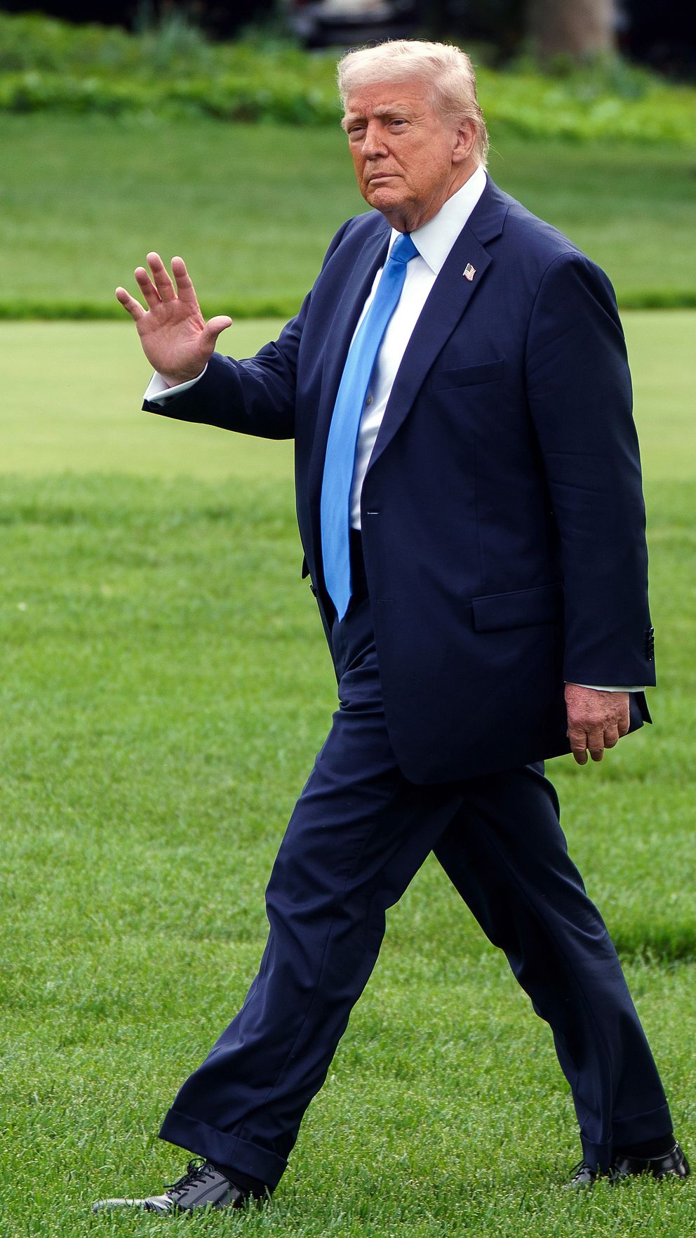 Donald Trump går över gräsmatta – vinkandes.