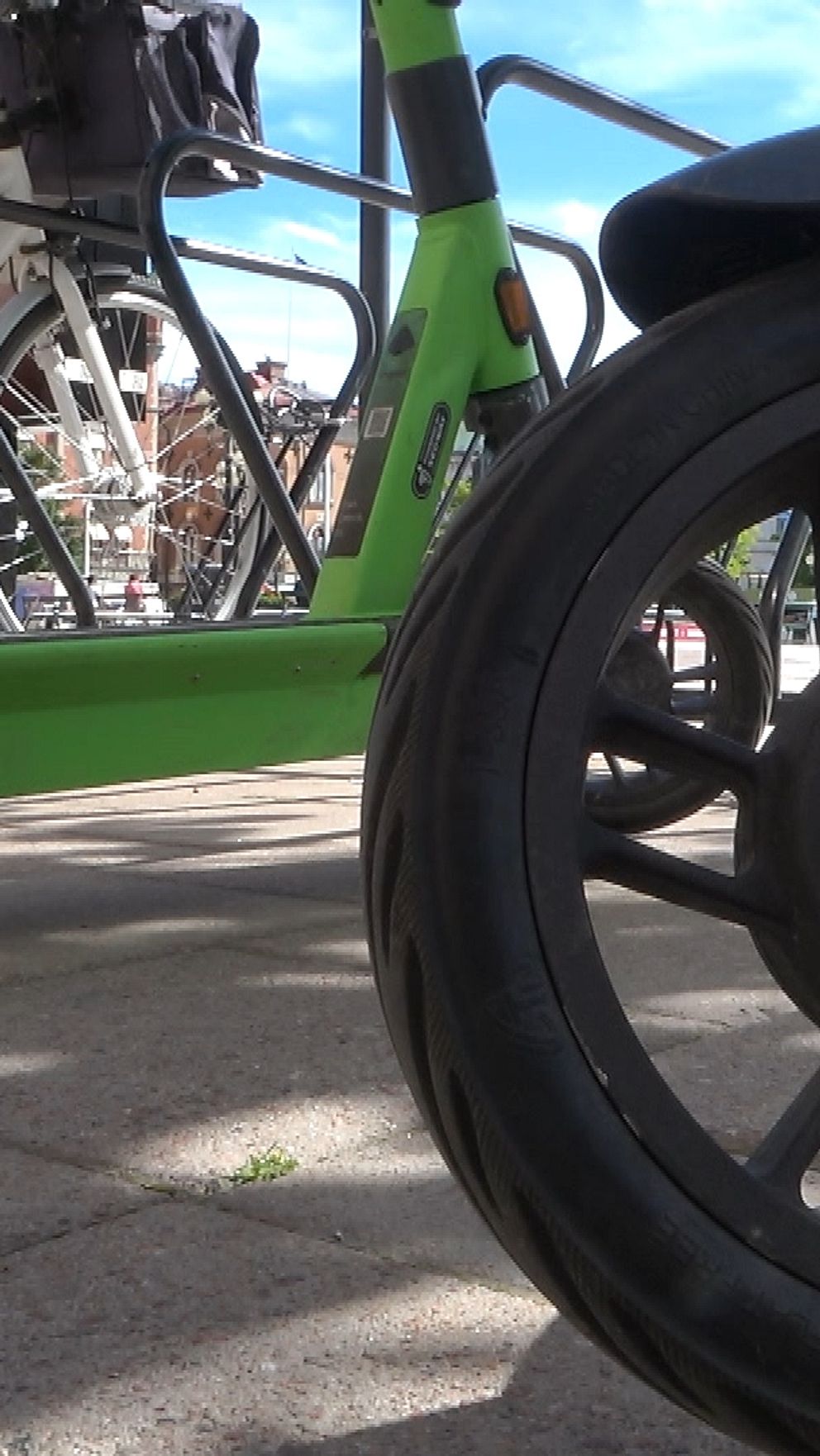 Närbild av elektrisk sparkcykel parkerad bredvid en cykel på trottoar.
