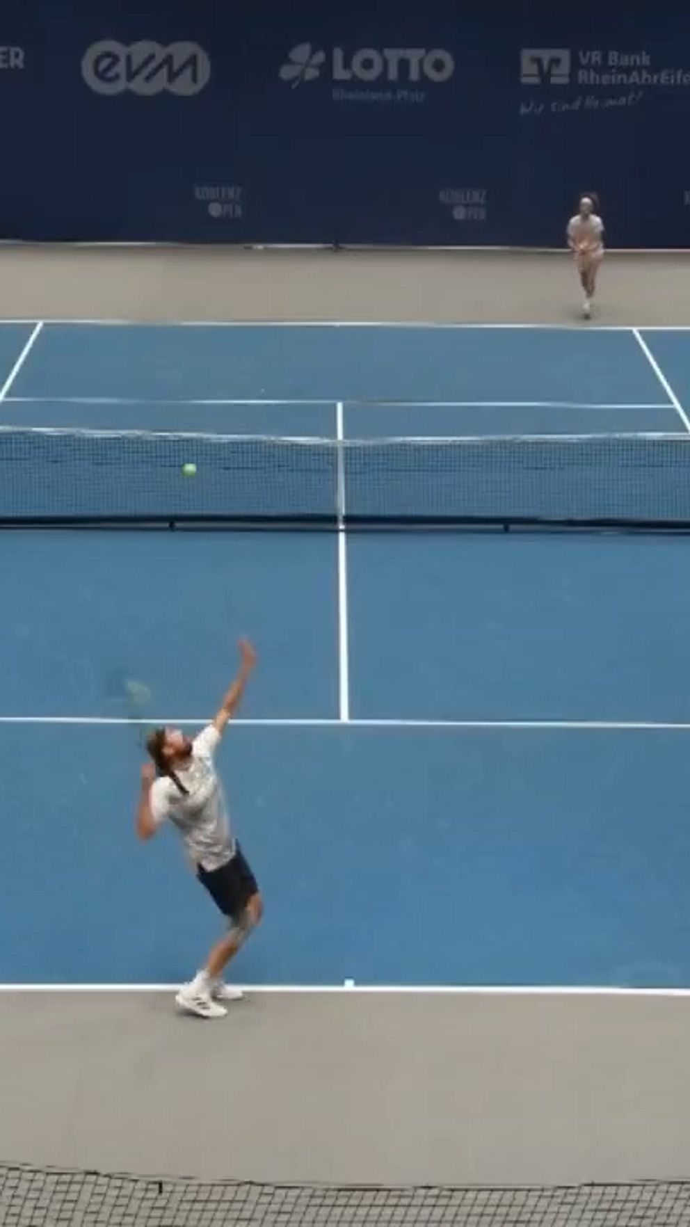 Bild på tennisplan där en match pågår och spelaren närmast bild ska serva.