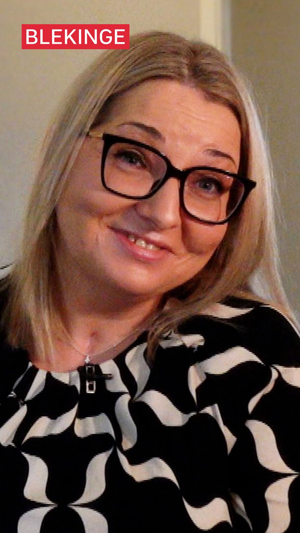 Kvinna med blont hår och svartvit mönstrad tröja, text ”Blekinge” uppe till vänster.