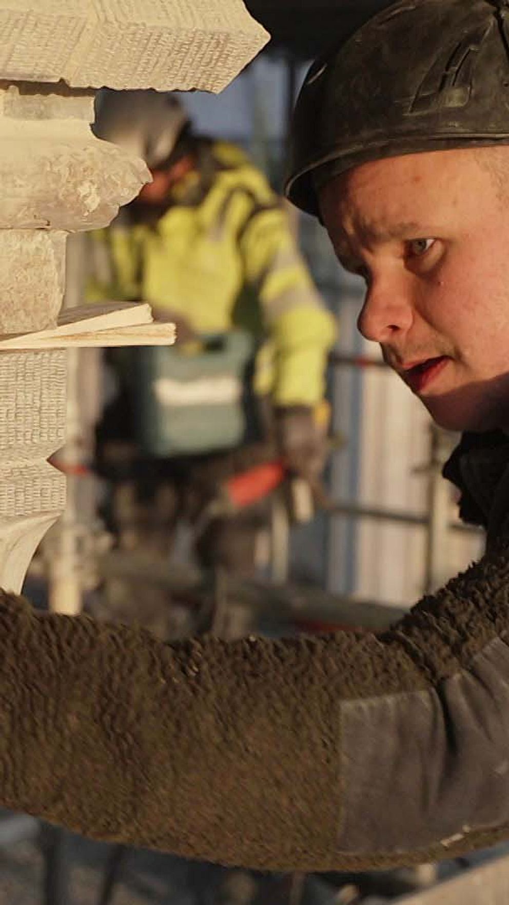 Stenhuggaren Philip Gullberg justerar stenblock vid byggarbetsplats.